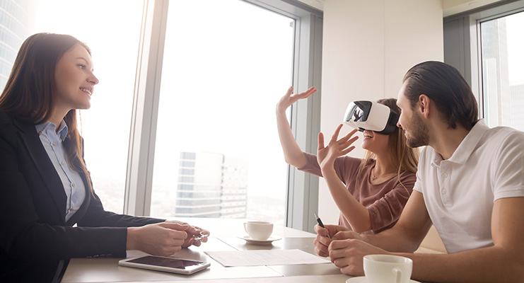 Couple are shown a real estate listing via VR in the agents office.